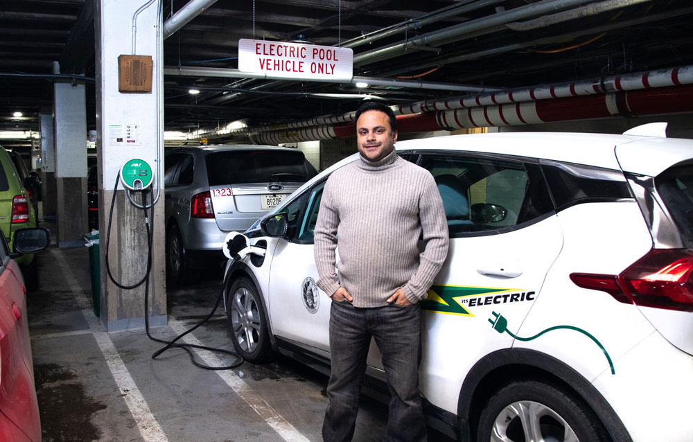man standing next to electric vehicle
