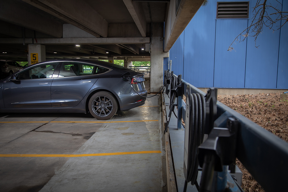Tesla at a workplace charging station in a parking garage.