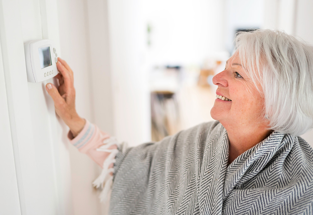 Woman setting the thermostat in her home.