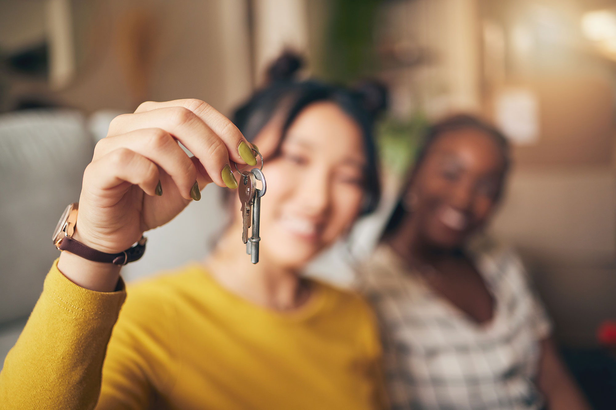 Young woman holding up keys to her new place.