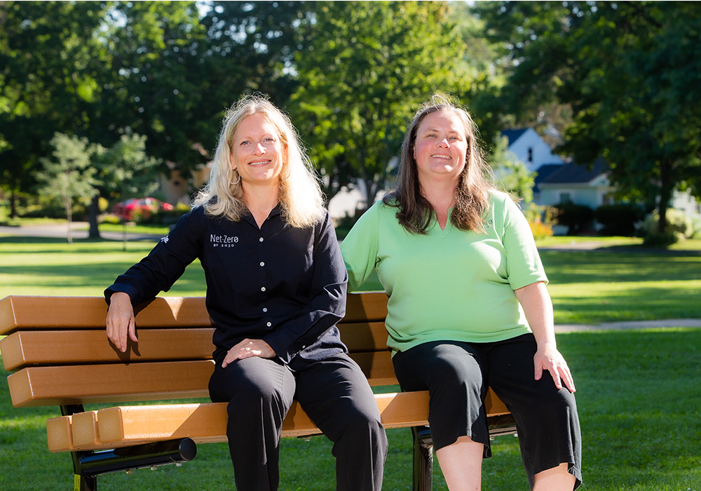Las expertas en energía de MGE, Laura Paprocki y Leah Samson, sentadas en una banca en un parque.