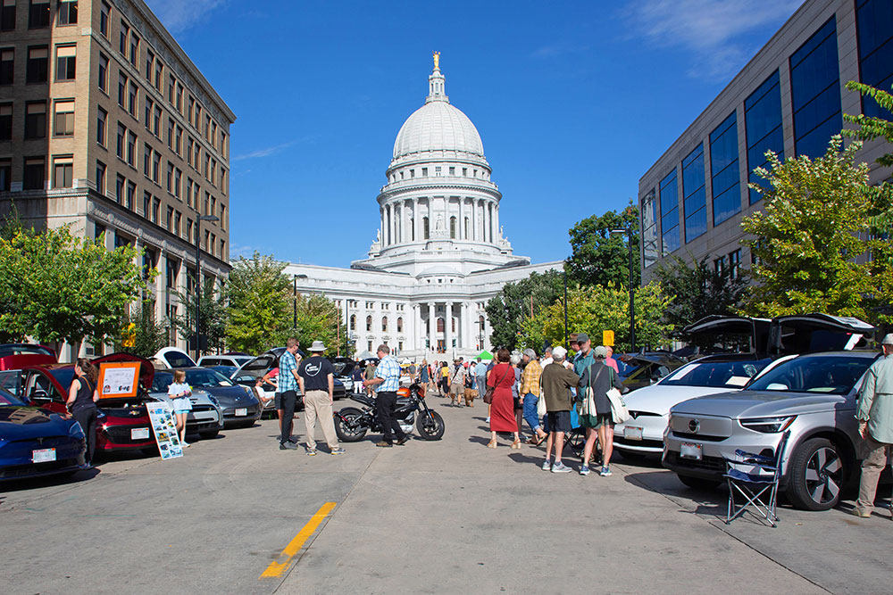 People looking at EVs parked on the Capitol Square in Madison.