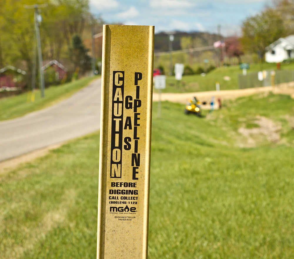 Yellow gas pipeline marker along a rural roadway.