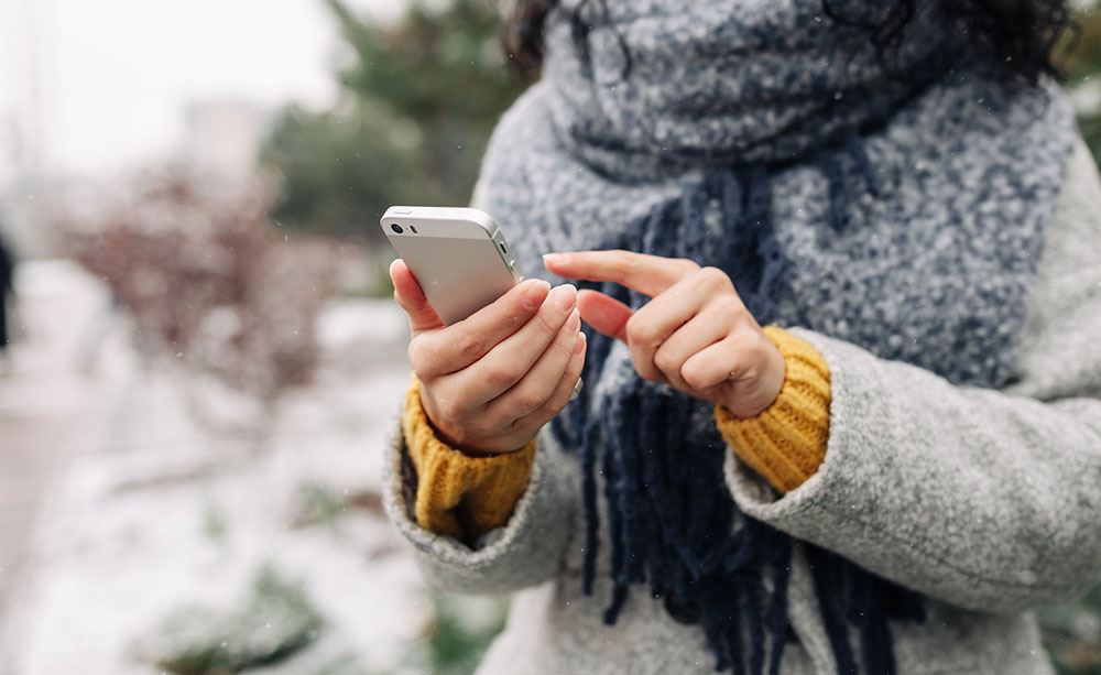 Woman bundled up outside in winter using her cell phone to make a call.