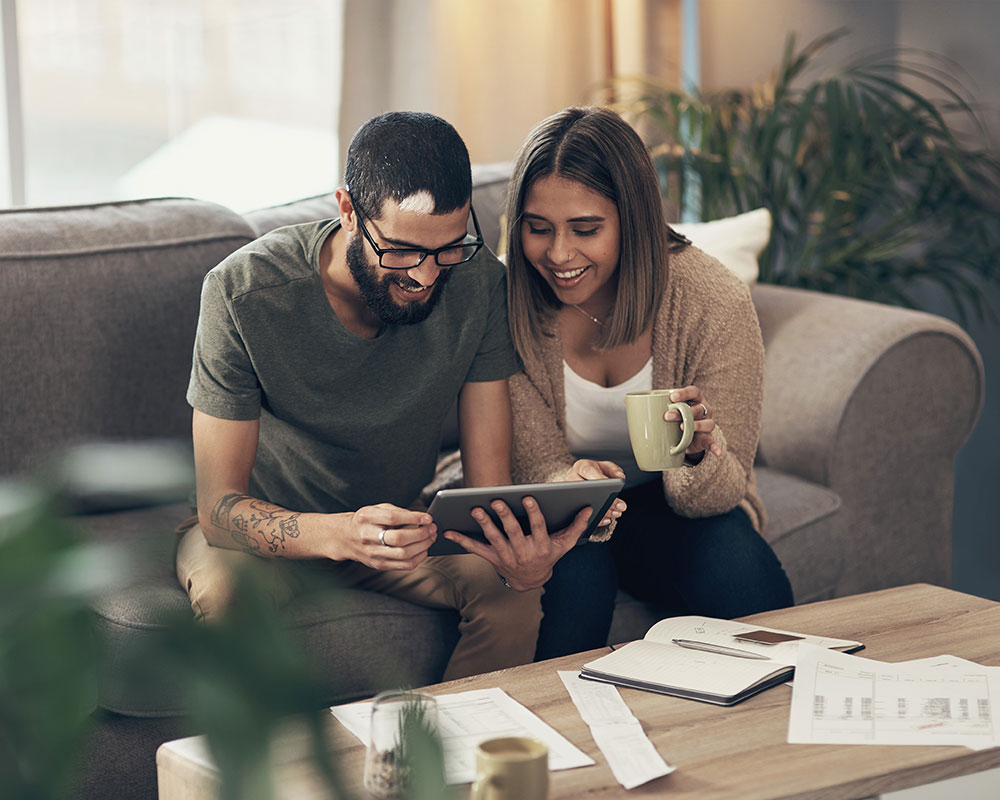 Couple on couch managing bills with laptop