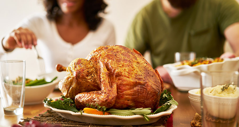 Comida tradicional de Acción de Gracias con pavo asado en un plato sobre una mesa.
