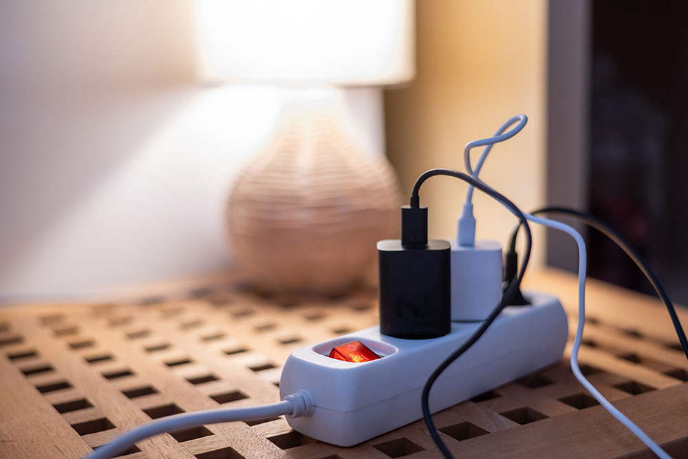 Powerstrip sitting on table with chargers plugged into it