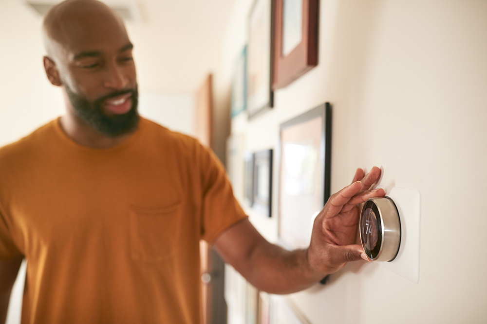 African American man adjusting a smart thermostat at home