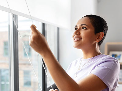 Mujer cerrando las persianas de una ventana de su apartamento