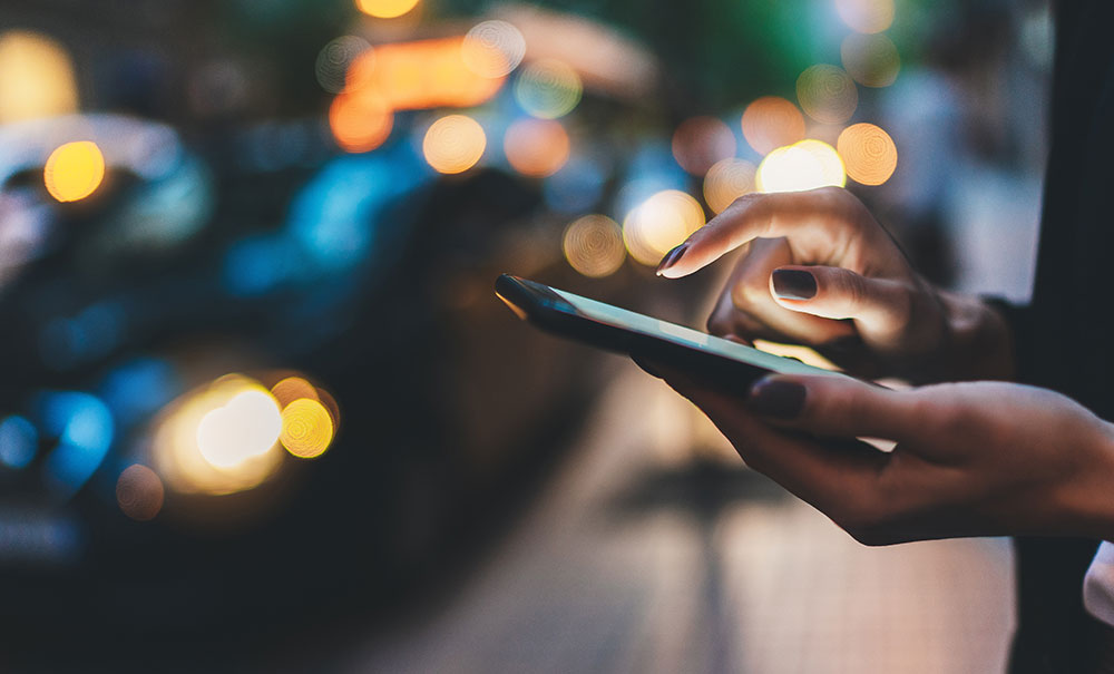 using mobile phone outside along a city street at night