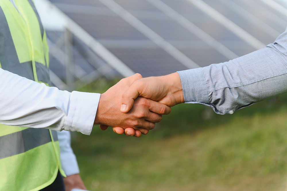 Shaking hands in front of solar array.