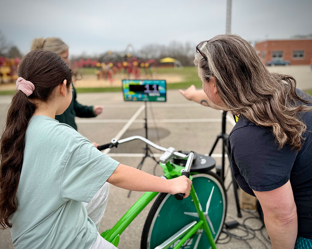 MGE shows a student how to use the Pedal Power Bike