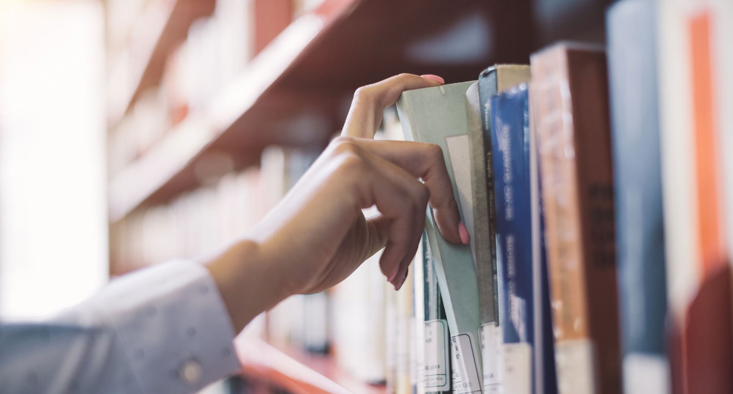Pulling a book from a shelf at a library.