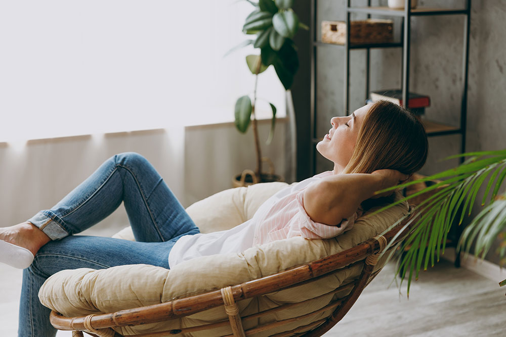 Woman relaxing in comfy papasan chair at home