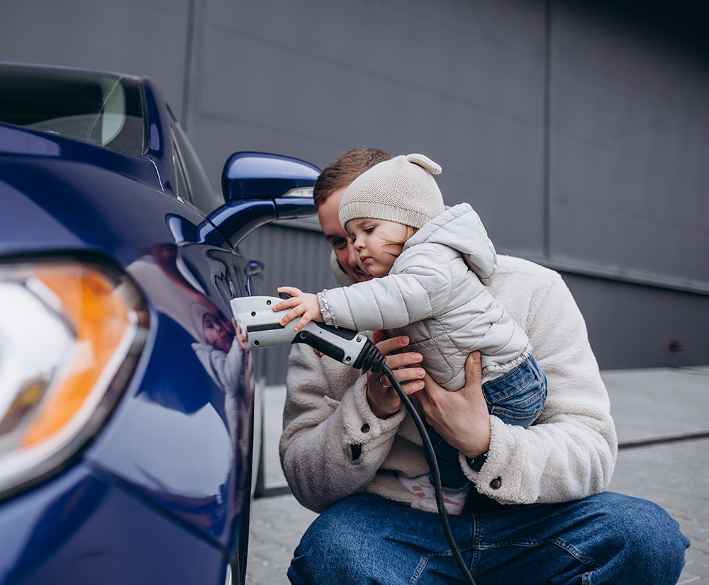 Child helping plug a charger into an electric vehicle
