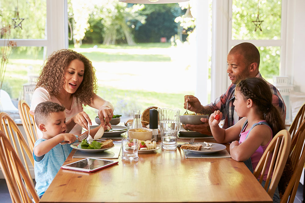 Family of four eating a meal together at dining room table