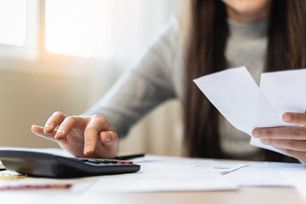 woman using calculator while paying bills