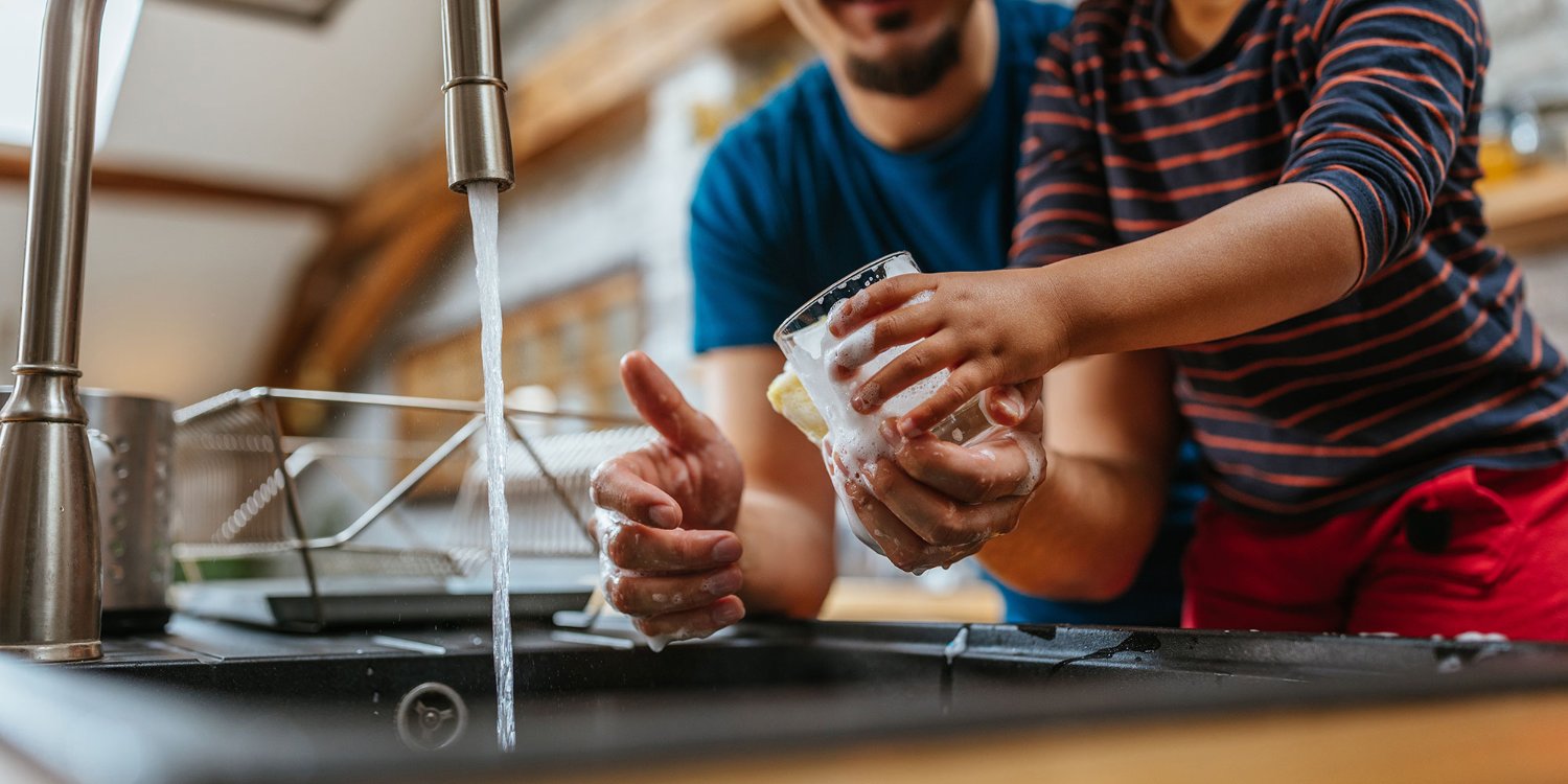 Dad and daughter washing dishes in kitchen sink